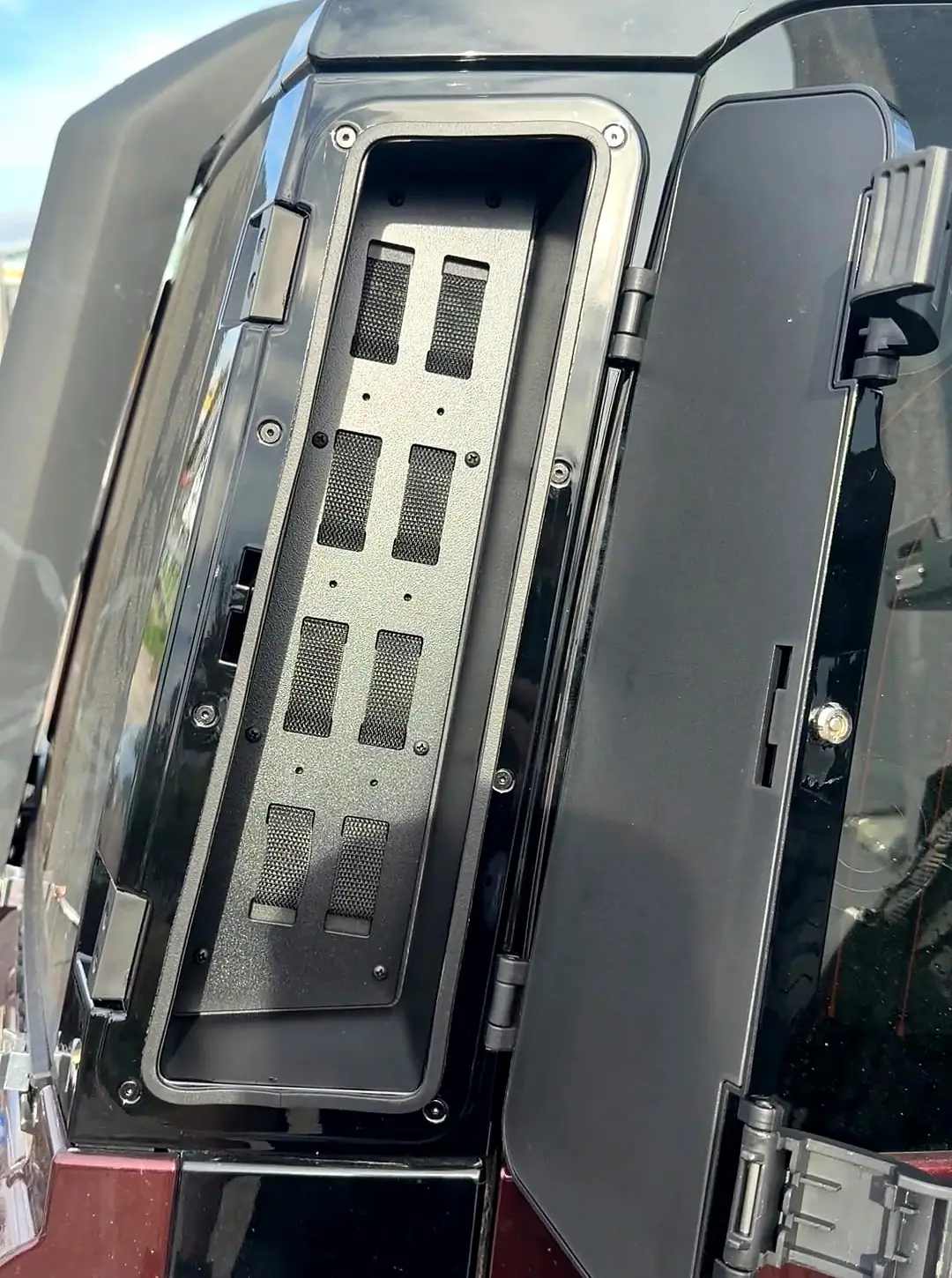 D-pillar storage box opened, showing the empty compartment and the door