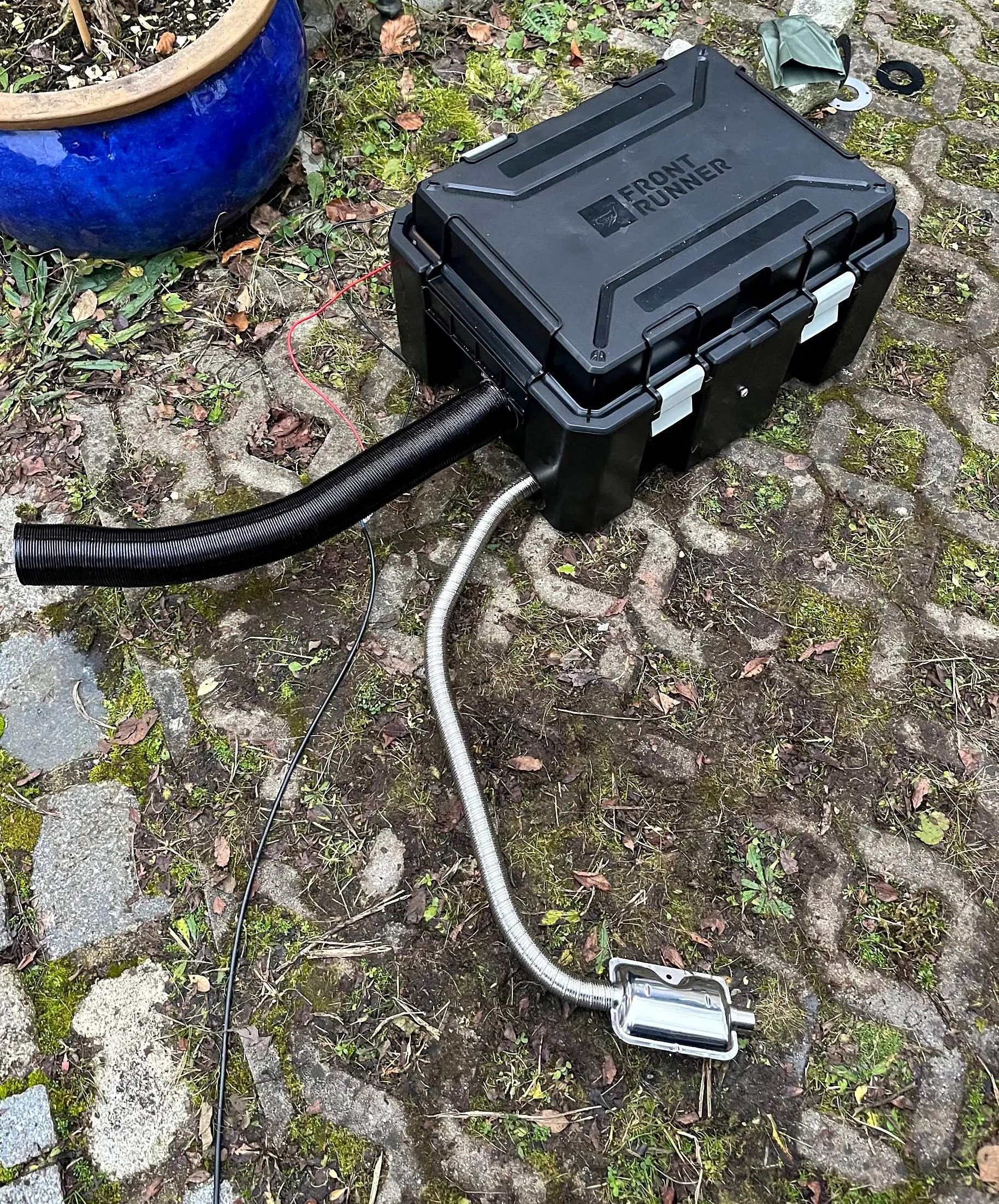 Front Runner Wolf Pack Pro box with a diesel heater inside, black warm-air duct and stainless exhaust with silencer