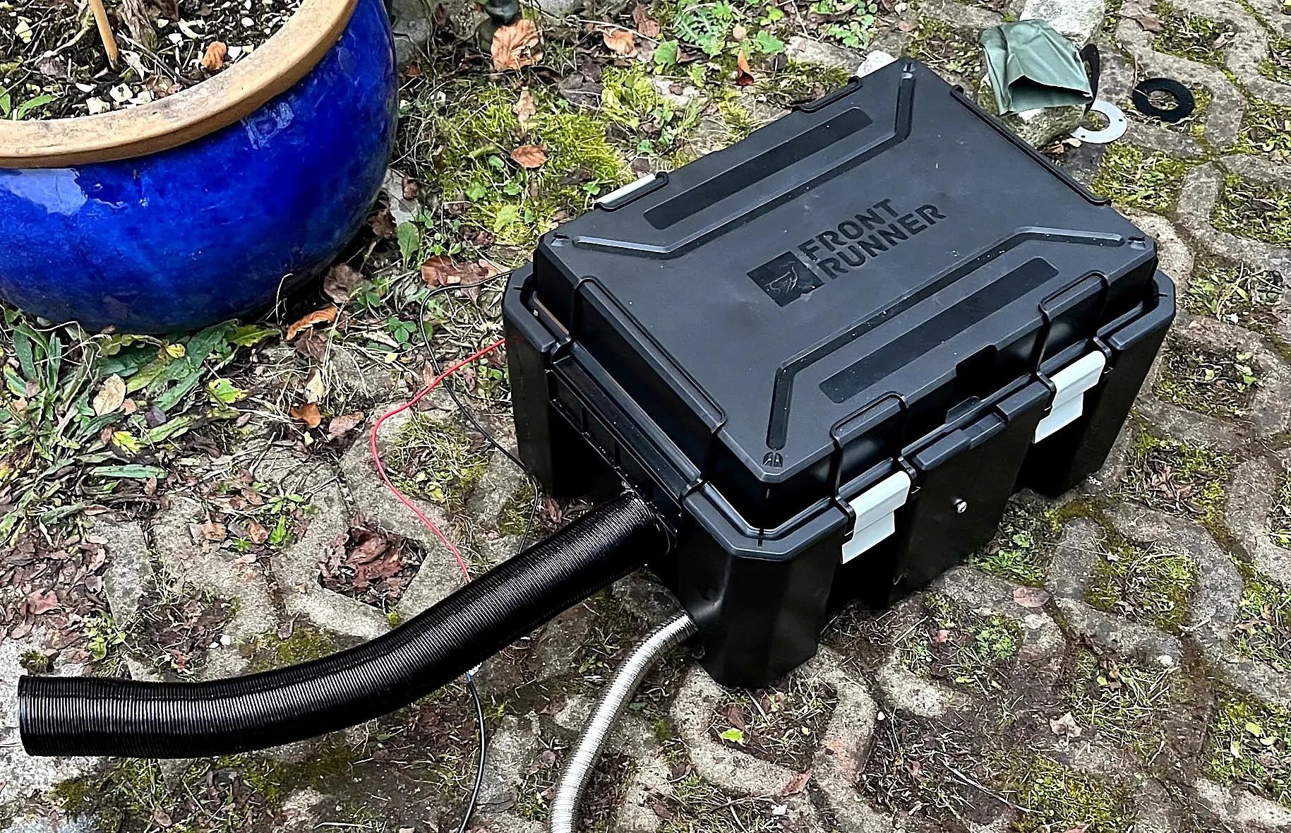 Front Runner Wolf Pack Pro box with a diesel heater inside, black warm-air duct and stainless exhaust with silencer