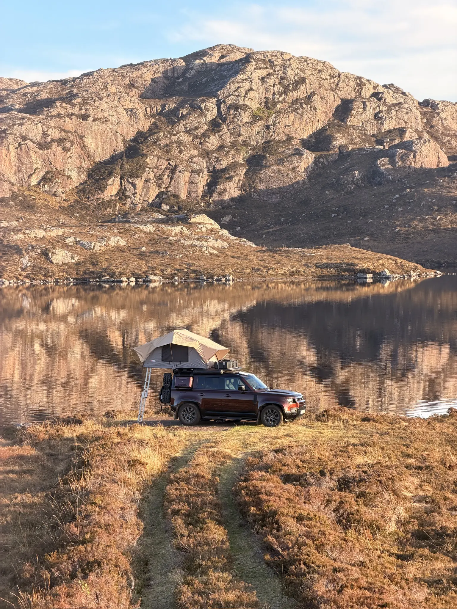 Defender with rooftop tent at a loch